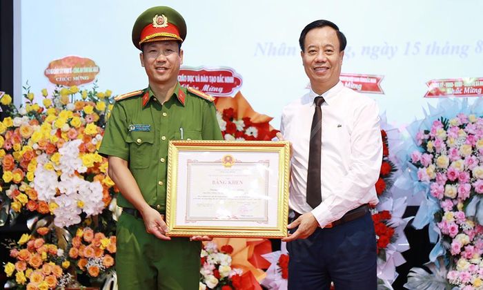 Đồng chí Đinh Đức Cảnh trao Bằng khen của Chủ tịch UBND tỉnh cho Thượng tá Nguyễn Tiến Dũng, Trưởng Công an xã vì có thành tích xuất sắc trong phong trào toàn dân bảo vệ an ninh Tổ quốc.