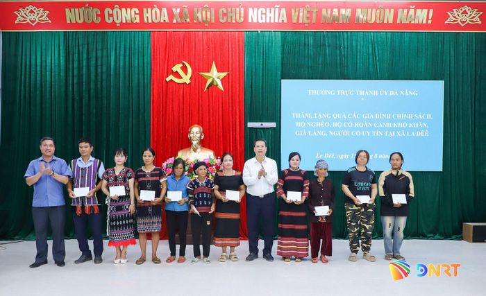 Chủ tịch UBND thành phố Nguyễn Mạnh Hùng (thứ 5, phải sang) và Phó Chủ tịch UBND thành phố Phan Thái Bình (ngoài cùng, bên trái) trao quà cho các hộ nghèo tại xã La Dêê. Ảnh: NGỌC PHÚ