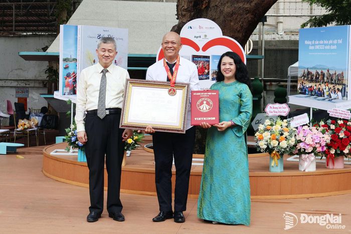 Nghệ sĩ nhiếp ảnh Nguyễn Á nhận bằng tôn vinh của Tổ chức Kỷ lục Việt Nam (VietKings) trong buổi triển lãm. Ảnh: Nguyệt Hà