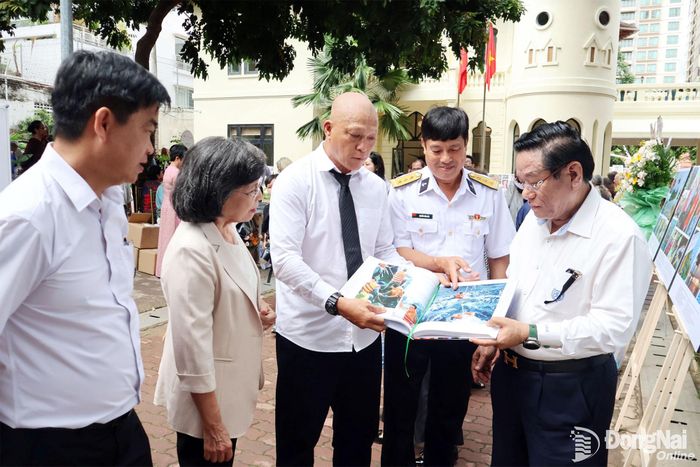 Nghệ sĩ nhiếp ảnh Nguyễn Á (giữa) giới thiệu tấm hình ông chụp Thượng tá Nguyễn Văn Lâm (thứ 2 từ phải sang), nguyên Chỉ huy trưởng Nhà giàn DKI/15, Vùng 2 Hải quân có mặt giao lưu tại triển lãm. Ảnh: Nguyệt Hà