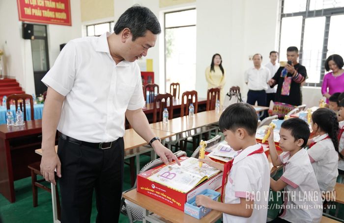 Đồng chí Nguyễn Cảnh Toàn, Phó Bí thư Tỉnh ủy, Chủ tịch UBND tỉnh hướng dẫn các em học sinh sử dụng bộ sách, bút chấm đọc - học tiếng Anh