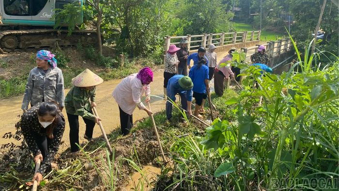 Cán bộ, công chức và người dân thu dọn đất đá, vệ sinh tuyến đường tại thôn Vành.