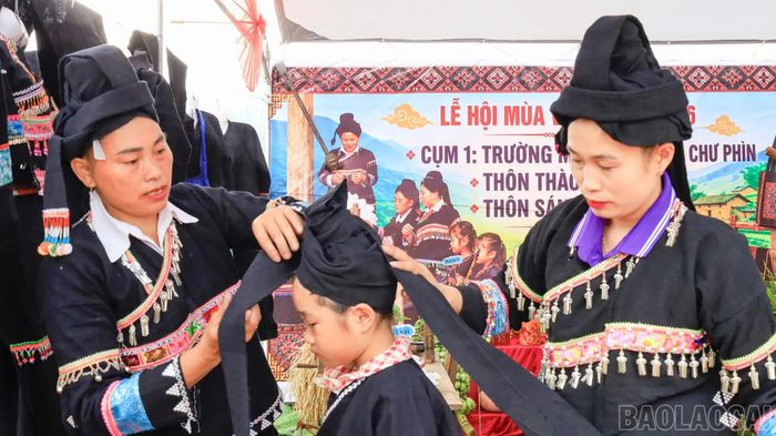 Phụ nữ dân tộc Thu Lao ở xã Sín Chéng giúp bé gái mặc trang phục truyền thống.