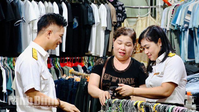 Cán bộ Thuế cơ sở 10 hướng dẫn hộ kinh doanh tại chợ Bầu, phường Phủ Lý thực hiện kê khai, nộp thuế thông qua ứng dụng điện tử.