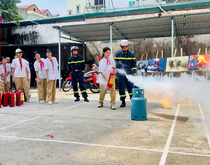Cảnh sát PCCC hướng dẫn các em học sinh sử dụng bình cứu hoả. Ảnh: Đức Tuấn