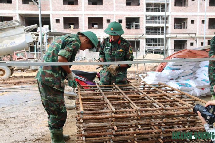 Lực lượng bộ đội và công nhân cùng góp sức hoàn thiện ngôi trường nội trú liên cấp phục vụ học sinh vùng biên. (Ảnh: Song Hoàng)