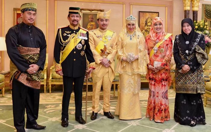Trong một nghi lễ, Quốc vương Hassanal Bolkiah nắm tay Hoàng tử Malik đặt lên đầu bà Adawiyyah như biểu tượng ban phước lành.