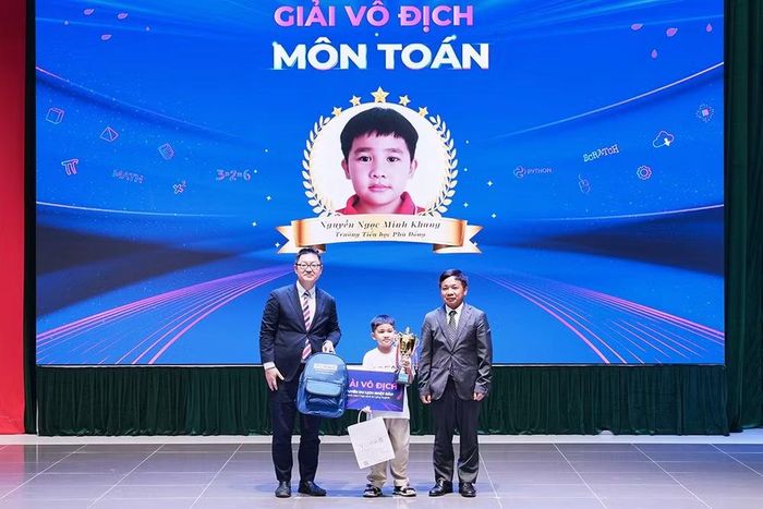 Đại diện Ban tổ chức trao giải vô địch môn Toán của Kỳ thi tặng thí sinh Nguyễn Ngọc Minh Khang, Trường tiểu học Phù Đổng. (Ảnh: Ban tổ chức cung cấp)