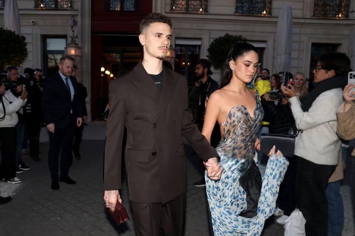Kim sánh đôi Romeo tại Paris Fashion Week tháng 3/2025, khi gia đình Beckham tới ủng hộ bộ sưu tập mới của Victoria. Cô chọn thiết kế xuyên thấu in hoa, phần thân dựng phom và tà vải lớn, phối cùng quần cạp gập.