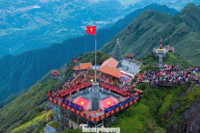 Giữa không gian núi rừng hùng vĩ, trong làn mây bảng lảng trên đỉnh Fansipan, lá cờ đỏ sao vàng tung bay trên nền trời xanh.