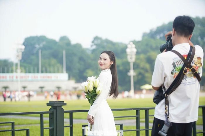Nhiều cô gái lựa chọn áo dài trắng truyền thống, kết hợp nón lá, khăn quàng cờ đỏ sao vàng làm điểm nhấn. Nhiều người cầm lá cờ nhỏ trên tay tạo dáng.