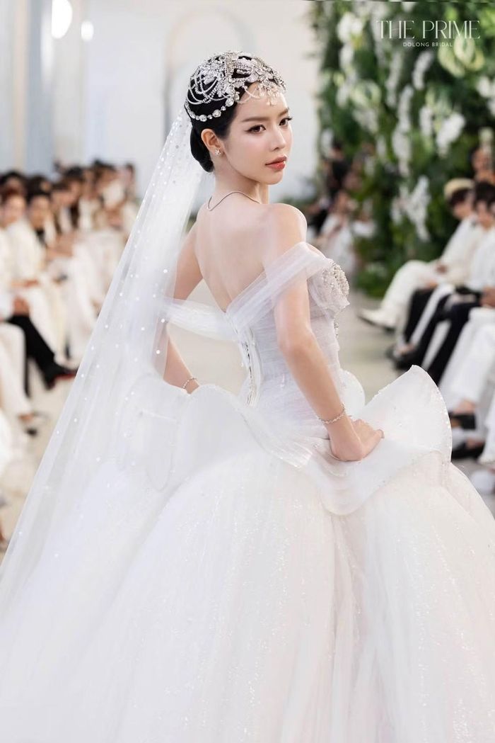 Thanh Thủy kết hợp váy cưới với khăn voan dài và phụ kiện đính đá trên tóc. Khi xoay người ở cuối đường băng, cô khoe phần lưng váy được xử lý bằng chất liệu trong suốt. Phong thái mềm mại của hoa hậu phù hợp không khí lãng mạn của bộ sưu tập.