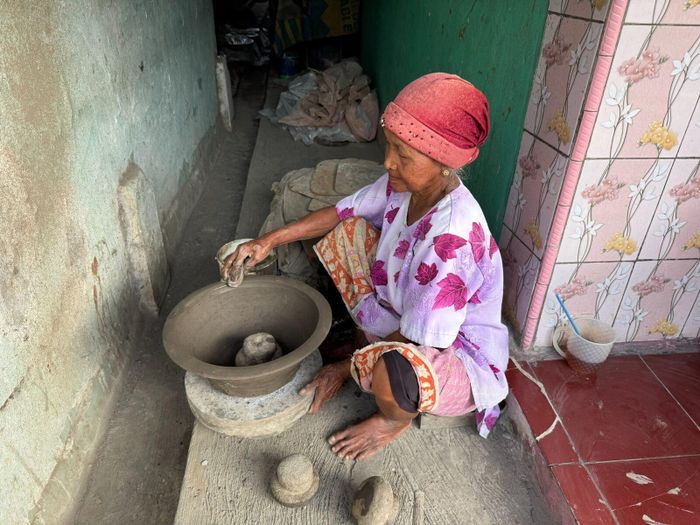 Người phụ nữ đang điều khiển bàn xoay để hoàn thành sản phẩm.