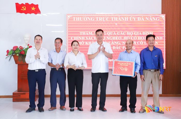 Bí thư Thành ủy Lê Ngọc Quang (thứ 3, bên phải sang) tặng quà của Thường trực Thành ủy cho Đảng ủy xã Đắc Pring. Ảnh: NGỌC PHÚ