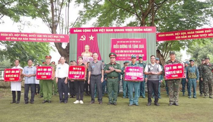 Đại tá Đinh Văn Thê và lãnh đạo xã tặng quà chúc mừng các đơn vị hoàn thành tốt cuộc diễn tập. Ảnh: Vĩnh Hoàng