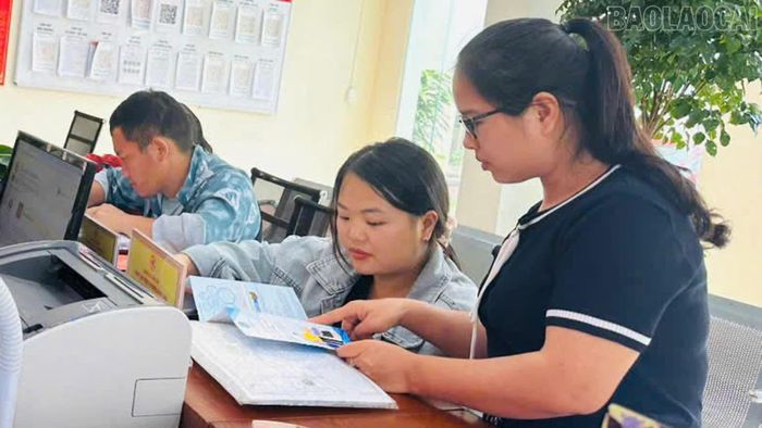 Chị Tráng Thị Nguyệt tư vấn chính sách bảo hiểm y tế hộ gia đình cho người dân.