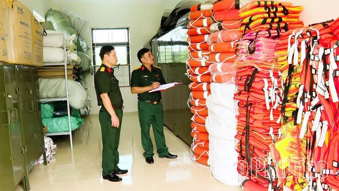 Thiếu tá Phan Ngọc Sang (bên phải) kiểm tra vật tư, trang thiết bị phòng, chống thiên tai tại kho tập kết của Ban CHQS xã Vĩnh Thành.