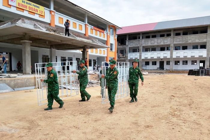 Bộ đội Đồn Biên phòng Tả Gia Khâu tham gia vận chuyển, lắp đặt các hạng mục của Phổ thông nội trú Tiểu học và Trung học cơ sở Pha Long. Ảnh: Duy Cường
