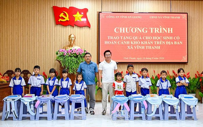 Phó Bí thư Thường trực Đảng uỷ xã Vĩnh Thanh Nguyễn Quốc Liêm (bên trái) và đại diện nhà tài trợ trao quà cho học sinh có hoàn cảnh khó khăn trên địa bàn xã.