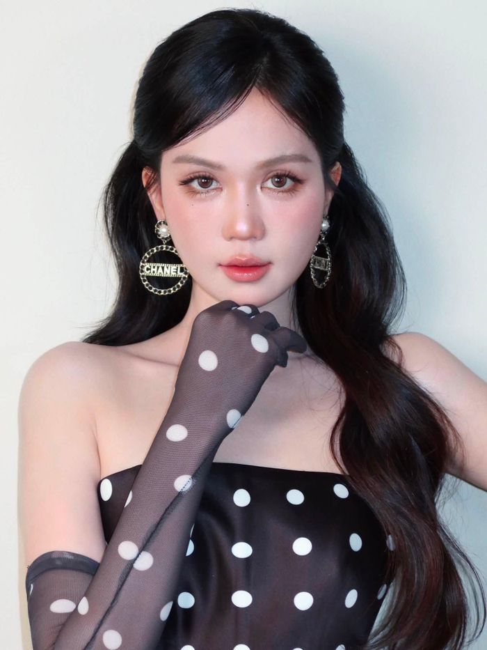 Họa tiết chấm bi trắng trên nền đen mang hơi hướng retro, trong khi phom váy ngắn và đường cắt hiện đại khiến tổng thể trở nên trẻ trung hơn. Đôi găng tay xuyên thấu đồng họa tiết kéo dài gần hết cánh tay cũng là chi tiết đáng chú ý, giúp một chiếc váy chấm bi quen thuộc có thêm nét cá tính.