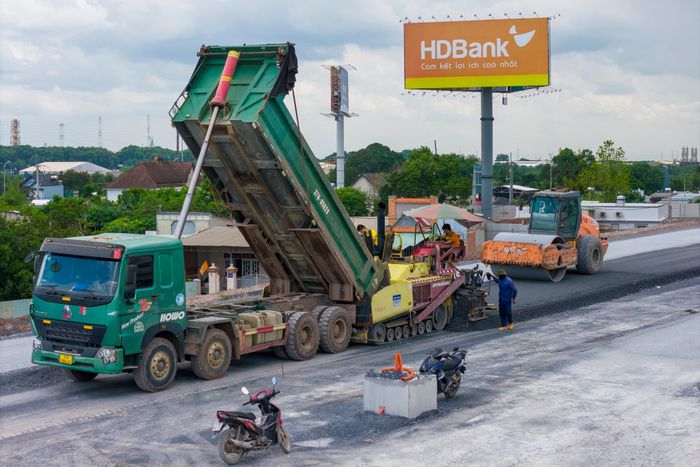  Xe ben liên tục vận chuyển vật liệu, máy rải và xe lu nối nhau hoàn thiện từng lớp mặt đường 
