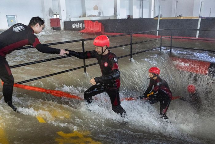 Người tham gia chống chọi với dòng nước dâng cao trong buổi huấn luyện kỹ năng ứng phó bão tại Lvxing Base, Hàng Châu, tỉnh Chiết Giang, Trung Quốc, ngày 15/7. Ảnh: Reuters.