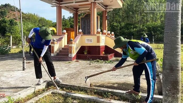 Dọn vệ sinh, phát cỏ tại Nhà bia ghi tên liệt sĩ xã Vĩnh Quang. (Ảnh: PHÚC THẮNG)