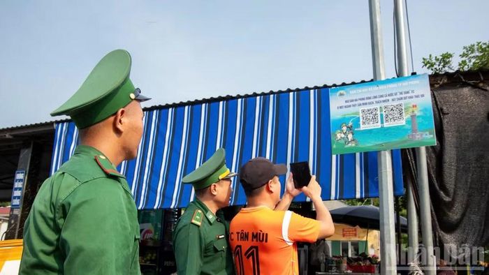Cán bộ, chiến sĩ Biên phòng thành phố hướng dẫn ngư dân quét mã “QR kép”.