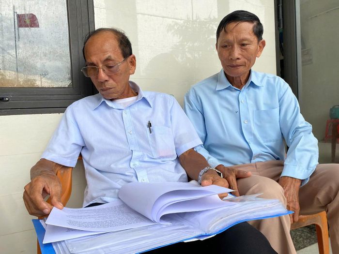 Hai cựu du kích Lê Quốc Thạnh (bên trái) và Nguyễn Xuân Lãnh lật lại nhưng bút tích về chiến trường Triệu Trạch, Quảng Trị.
