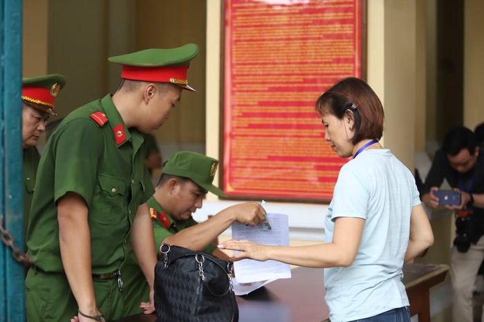 Cảnh sát kiểm tra giấy tờ người vào phòng xử án.