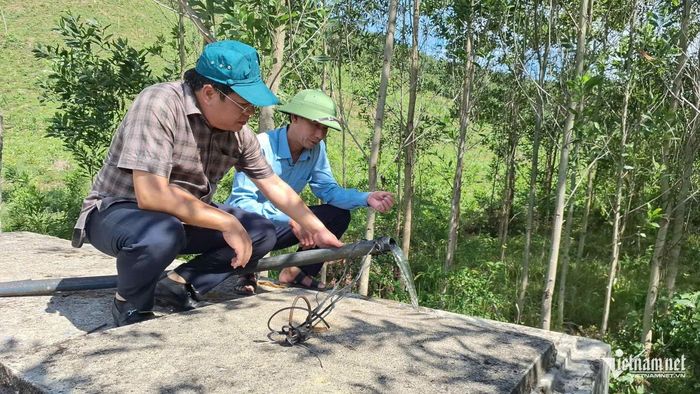 Ông Đinh Anh Tuấn - Phó Chủ tịch UBND xã Kim Điền (trái) đi kiểm tra công trình nước tự chảy trên địa bàn xã. Ảnh: Phạm Tiến