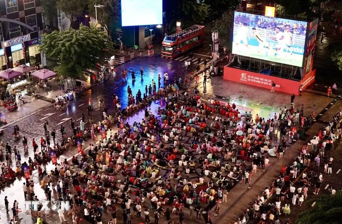 Người hâm mộ Thành phố Hồ Chí Minh phải đội mưa cổ vũ cho đội tuyển Việt Nam trong những phút đầu của trận đấu bán kết lượt đi. (Ảnh: Trung Tuyến/TTXVN)