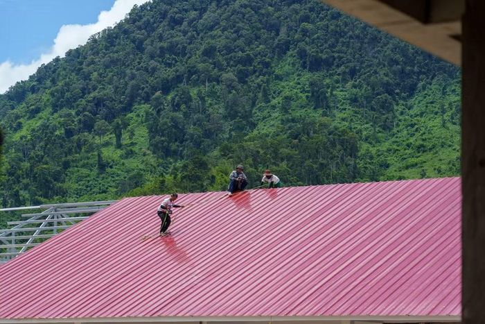 Công nhân kiểm tra kỹ lưỡng các khớp nối tôn, đảm bảo chất lượng cho công trình. (Ảnh: Thanh Phong/Vietnam+)
