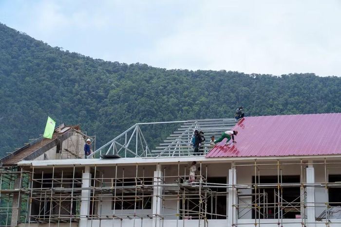Các công nhân miệt mài thi công lắp đặt hệ thống mái che chống bão cho khối nhà. (Ảnh: Thanh Phong/Vietnam+)