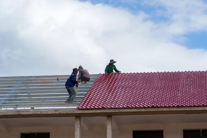 Công nhân đo đạc, kiểm tra kỹ lưỡng độ chính xác của kết cấu thép khung mái trước khi tiến hành lợp. (Ảnh: Thanh Phong/Vietnam+)