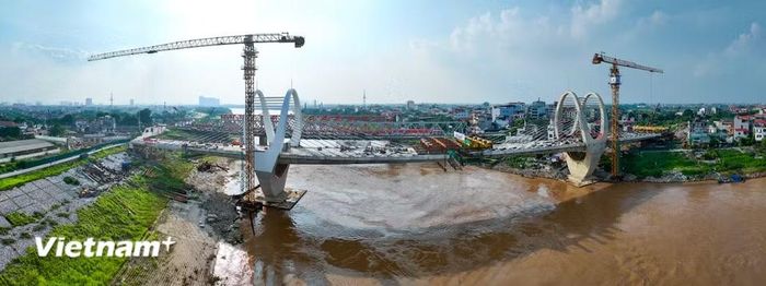 Hai phần nhịp chính cầu Đuống mới đã tiến gần vị trí kết nối giữa sông. (Ảnh: Hoài Nam/Vietnam+)