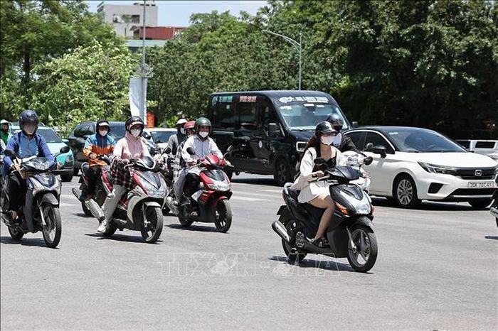 Người dân sử dụng áo chống nắng, khẩu trang khi tham gia giao thông. Ảnh: Vũ Quang/TTXVN