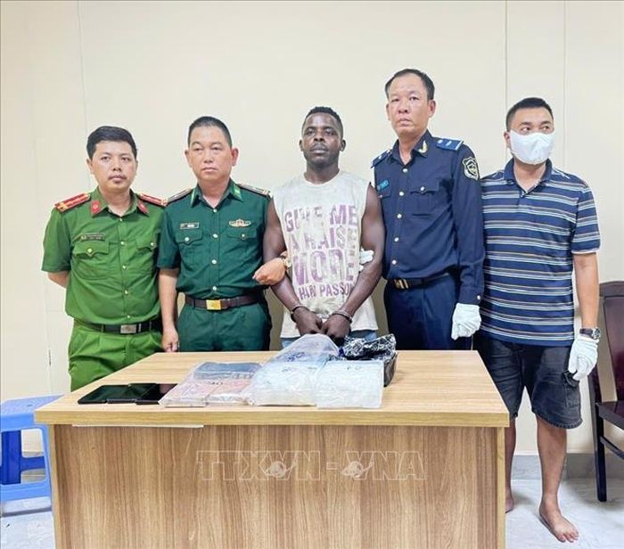 Đối tượng Izuchukwu Calistus Odionye bị bắt giữ nhận kiện hàng có cất giấu 2kg nghi ma túy tổng hợp dạng đá và 2 bánh nghi heroin. Ảnh: TTXVN phát