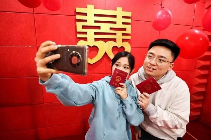 Chụp ảnh tự sướng sau khi nhận giấy đăng ký kết hôn tại ngân hàng. Ảnh: Sina.