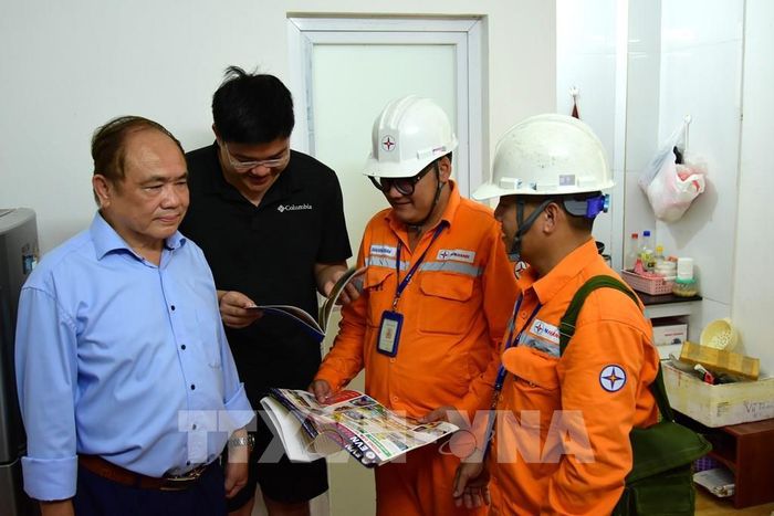 Công nhân EVNHANOI trao đổi với khách hàng về dịch vụ kỹ thuật điện sau công tơ, góp phần giúp người dân chủ động kiểm tra, sửa chữa và sử dụng điện an toàn. Ảnh: Quốc Lũy - TTXVN