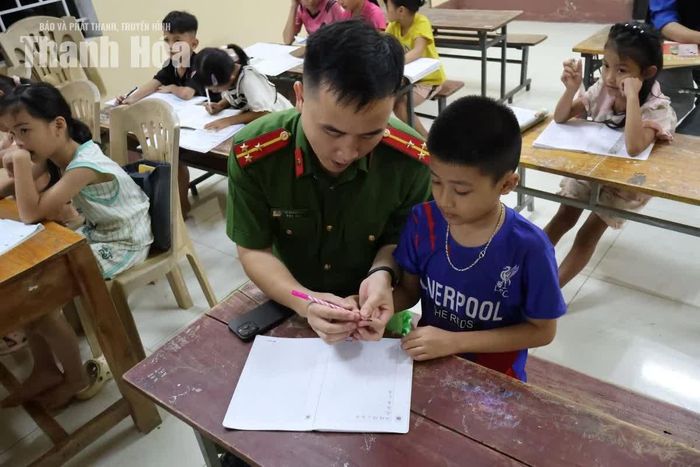 Với những em còn lúng túng, cán bộ đứng lớp hướng dẫn từ cách cầm bút đến từng bài tập trong vở.