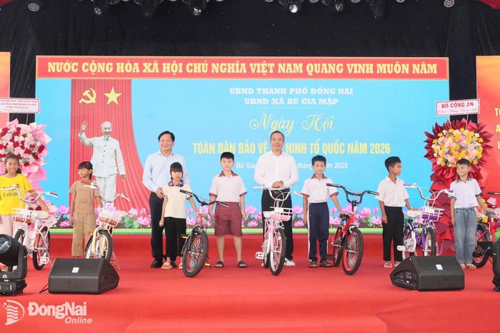 Thành ủy viên, Phó Chủ tịch HĐND thành phố Trần Văn Mi và lãnh đạo Ủy ban MTTQ Việt Nam thành phố tặng xe đạp cho học sinh có hoàn cành khó khăn. Ảnh: Quang Minh.