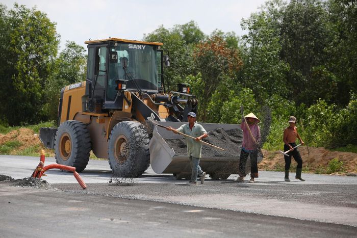 Công nhân, máy móc chia thành nhiều mũi thi công các hạng mục như thảm nhựa, cống rảnh, đắp đất trên công trường.