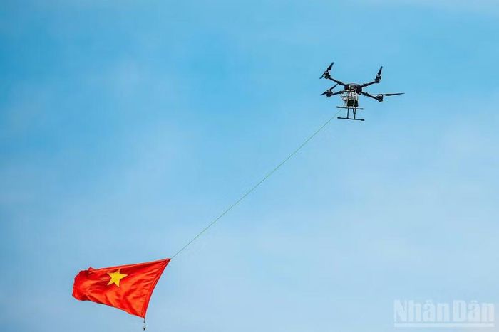 Phương tiện bay không người lái thương hiệu Việt Nam H-X6 mang theo cờ Tổ quốc bay trên vùng nhận diện phòng không thuộc thao trường trước khán đài.