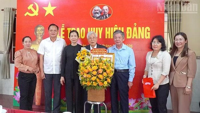 Bí thư Tỉnh ủy Đồng Tháp Ngô Chí Cường (thứ 3 từ phải qua) trao Huy hiệu Đảng và tặng hoa chúc mừng đồng chí Huỳnh Minh Đoàn. (Ảnh: Hữu Nghĩa)