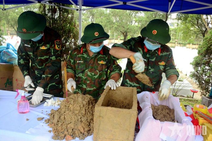 Thiếu tá QNCN Bùi Quốc Đạt (đứng giữa) cẩn trọng, tỉ mỉ trong việc lấy sinh phẩm xác định ADN, tìm lại thông tin liệt sĩ.