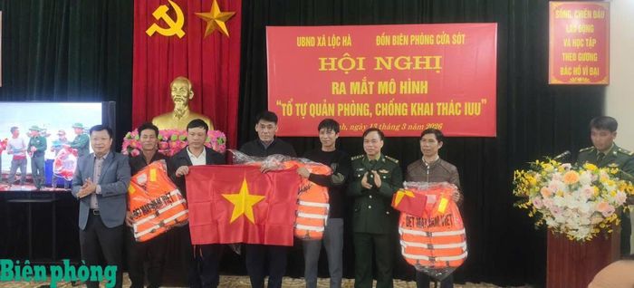Trung tá Lê Hữu Đồng tặng cờ Tổ quốc và áo phao cho ngư dân tại Lễ ra mắt mô hình “Tổ tự quản phòng, chống khai thác IUU”. Ảnh: Đơn vị cung cấp