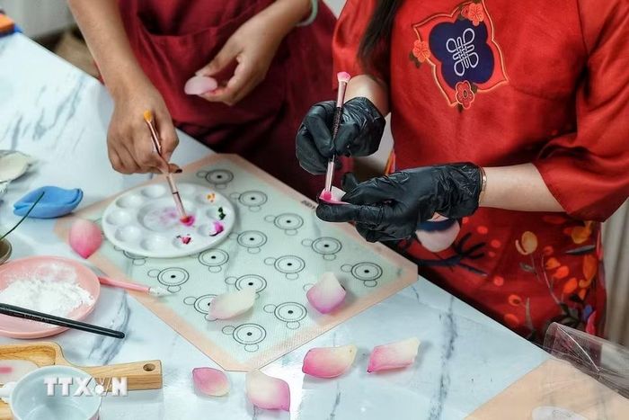 Người làm sử dụng màu thực phẩm để tạo sắc độ cho từng chi tiết bằng bột tò he, góp phần làm những cánh hoa có đường nét và màu sắc gần với hoa thật. (Ảnh: Phạm Tuấn Anh/TTXVN)