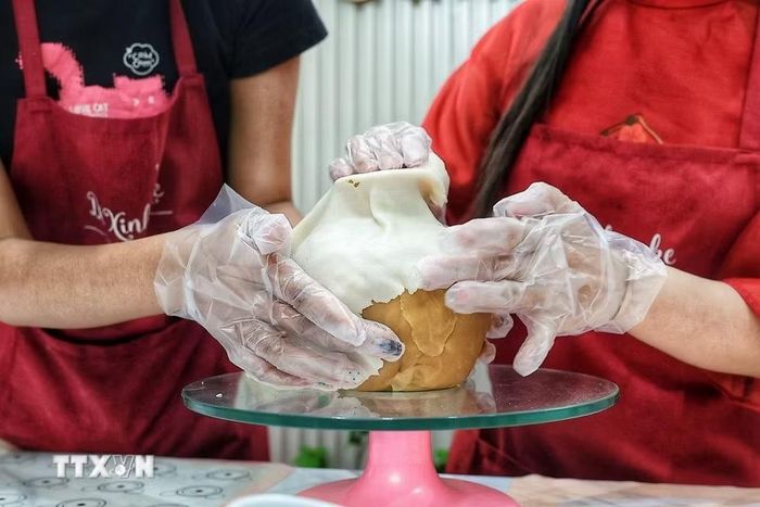 Từng bước định hình thành chiếc bình dùng để cắm những cành hoa làm bằng cách làm bánh Trung Thu. (Ảnh: Phạm Tuấn Anh/TTXVN)