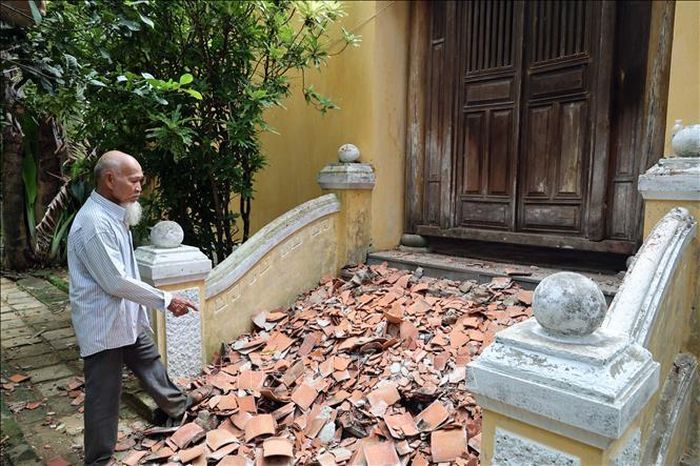 Ông Phan Ngẫu, người trông coi Nhà lưu niệm Phan Châu Trinh, bên đống ngói rơi vỡ nằm ngổn ngang trên bậc thềm.